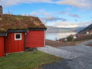 a red building with a grass roof with a view of a lake at Chalet Krampehaugen - FJS046 by Interhome in Utvik