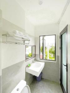 een witte badkamer met een wastafel en een raam bij Bap Homestay in Hội An
