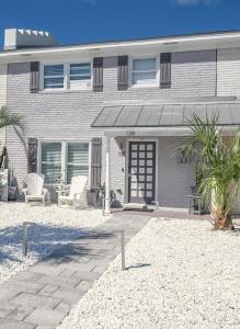 a house with chairs and a patio in front of it at Red Hot Retreat - Updated Holiday Isle Townhome on the Destin Harbor in Destin