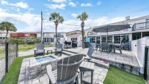 a patio with chairs and tables and an umbrella at Red Hot Retreat - Updated Holiday Isle Townhome on the Destin Harbor in Destin