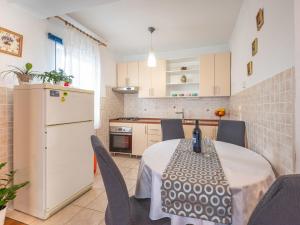 een keuken met een tafel met stoelen en een witte koelkast bij Apartment Ivana by Interhome in Jadranovo