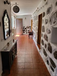 una sala de estar con una pared de piedra y una mesa. en Casa Rural LOS PINARES El Juncal de TEJEDA, en Tejeda