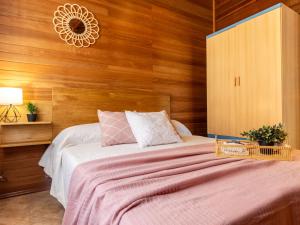 um quarto com uma cama grande e paredes de madeira em Chalet Tropical 2 by Interhome em Riumar