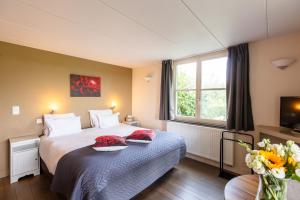 - une chambre avec un lit et un vase de fleurs dans l'établissement B&B Het Eycken Huys, à Aalter