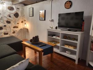 a living room with a flat screen tv on a white entertainment center at Casa Rural LOS PINARES El Juncal de TEJEDA in Tejeda