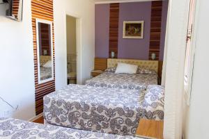 duas camas num quarto com paredes roxas em Hotel Fazenda Poços de Caldas em Poços de Caldas