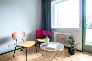 a room with chairs and a table with a vase of flowers at Flattering - Berlin in Berlin