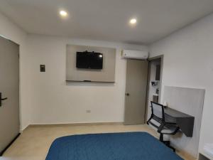 een slaapkamer met een bed en een televisie aan de muur bij San Marcos Hotel Guaymas in Guaymas