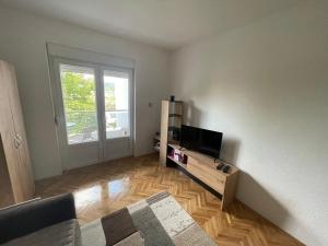 Apartman Zec Beli Sokobanja في سوكو بانيا: غرفة معيشة مع تلفزيون وأرضية خشبية +8 صور