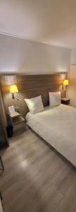 - une chambre avec un grand lit blanc et 2 oreillers dans l'établissement Crystal Hotel Saint Denis Basilique, à Saint-Denis