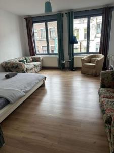a room with a bed and a couch and windows at The Bachelor Backpacker Spot in Brussels