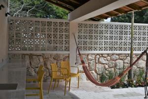 a patio with chairs and a hammock and a stone wall at Trilliza-Verde in Campeche