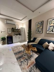 ein Wohnzimmer mit einem blauen Sofa und einem Tisch in der Unterkunft شقة مودرن في حي العقيق in Riad
