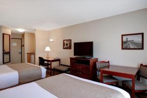 a hotel room with two beds and a flat screen tv at Days Inn by Wyndham Dawson Creek in Dawson Creek