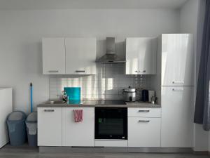 La cuisine est équipée de placards blancs et d'un four avec plaques de cuisson. dans l'établissement Sofieflat - Wallifornie, à Charleroi