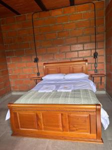 una cama de madera frente a una pared de ladrillo en HOTEL EMBRUJO CAMPESTRE, en Jardín
