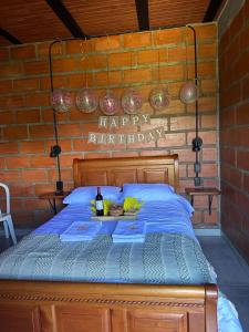 una cama con un signo de feliz cumpleaños en una pared de ladrillo en HOTEL EMBRUJO CAMPESTRE, en Jardín