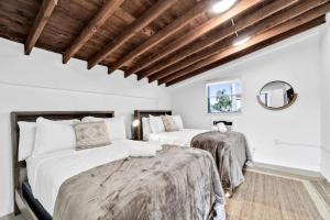 two beds in a room with white walls and wooden ceilings at Modern Pool Home Great for Families in Hollywood +38 photos