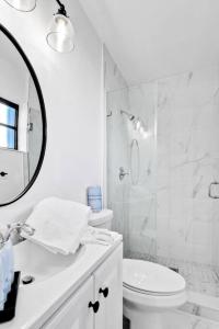 a white bathroom with a toilet and a mirror at Modern Pool Home Great for Families in Hollywood
