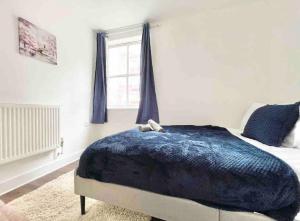 a bedroom with a bed with a blue blanket and a window at Exquisite Luxury Retreat in Southampton