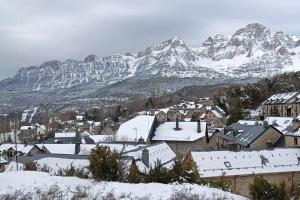 une ville recouverte de neige avec une montagne en arrière-plan dans l'établissement Ático en pleno pirineo, à El Pueyo de Jaca