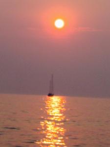 una barca a vela nell'oceano con il tramonto di Le Casette di Alice a Scoglitti