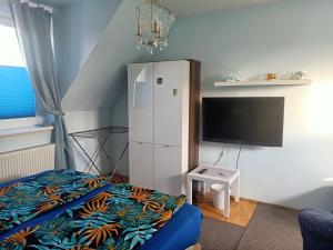 ein Schlafzimmer mit einem weißen Kühlschrank und einem TV in der Unterkunft Bukowy zakątek kwatera prywatna in Koszalin