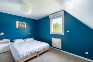 een blauwe slaapkamer met een bed en een raam bij Beautiful house in Trouville-sur-Mer in Trouville-sur-Mer