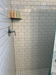 La salle de bains est pourvue de carrelage blanc, d'une douche et d'un distributeur de savon. dans l'établissement New Centennial Park Luxury Smart Home w Courtyard, à Fayetteville