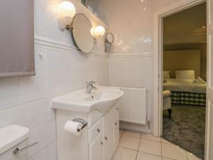 a white bathroom with a sink and a mirror at Clarence House in Dalton in Furness