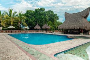 una piscina en un complejo con sombrilla de paja en Hotel Portón del Sol, en Santa Fe de Antioquia