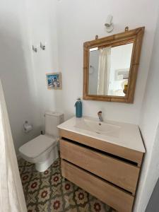 ein Badezimmer mit einem Waschbecken, einem WC und einem Spiegel in der Unterkunft Doña Lola Rooms in Conil de la Frontera