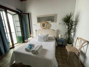 a bedroom with a white bed with towels on it at Doña Lola Rooms in Conil de la Frontera
