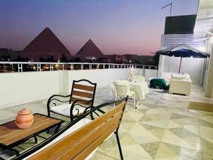 a balcony with a table and chairs and a view of the pyramids at La Perle Pyramids in Cairo