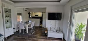 a living room with a dining table and a television on a wall at Vila Elena in Niš