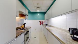 cocina grande con armarios blancos y techo verde en Marina Heights - Unique One Bedroom, en Dubái 7 fotos más