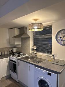 a kitchen with a sink and a clock on the wall at Stylish Studio flat - Watford Junction - Harry potter in Watford