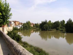 a river with a stone wall next to a city at Casa Rural Flor in Vadocondes