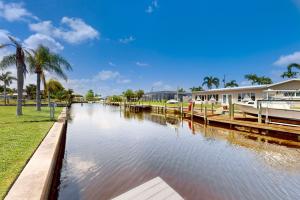 un canal avec des bateaux, des palmiers et une maison dans l'établissement Hip Harbour, à North Fort Myers