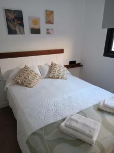 a white bed with two towels on top of it at APARTAMENTOS Posada Del Mar in Los Mártires