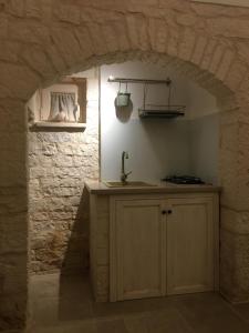 a kitchen with an archway in a stone wall at TRULLI LE 2 NICCHIE in Locorotondo