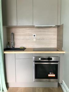 eine Küche mit weißen Schränken und einem schwarzen Backofen in der Unterkunft soleil et bateau in Courseulles-sur-Mer