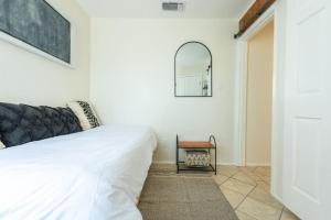 - une chambre avec un lit blanc et un miroir dans l'établissement Downtown Pearl Bungalow at Beer Ranch Project, à Wimberley