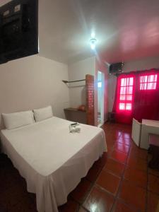 a bedroom with a white bed and a red window at Pousada das Tartarugas in Rio das Ostras