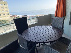 a wooden table and chairs on a balcony with the beach at Home of Neptune in Póvoa de Varzim