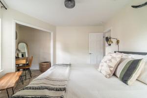 a white bedroom with a bed and a table at Downtown Lonestar Bungalow at Beer Ranch Project in Wimberley