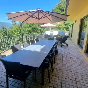 une table bleue, des chaises et un parasol sur la terrasse dans l'établissement Casa Picone - Gerês, à Ventosa