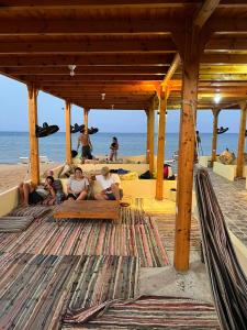 un grupo de personas sentadas bajo un pabellón en la playa en Star Dune Camp en Nuweiba