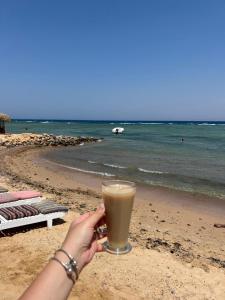 a woman holding a glass of coffee on the beach at Star Dune Camp in Nuweiba