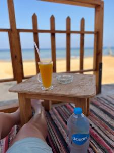a person with their feet on a table with a drink at Star Dune Camp in Nuweiba